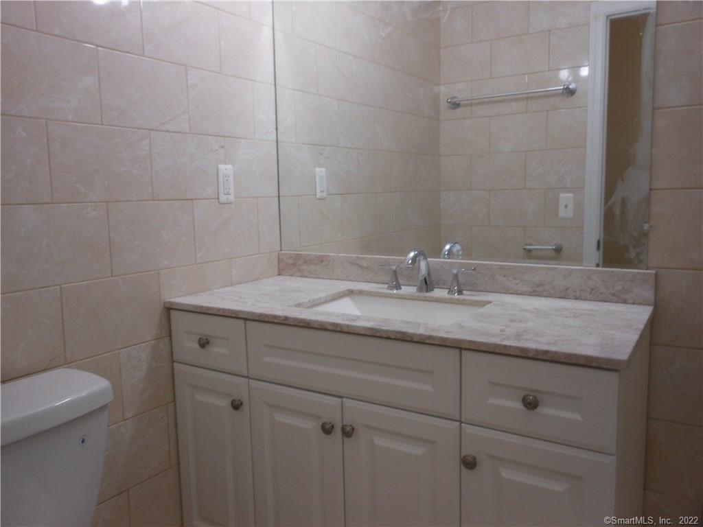 277 Whisconier Road, Unit B Brookfield, CT 06804 - Photo 9 of 10 a bathroom with a granite countertop sink a toilet and mirror