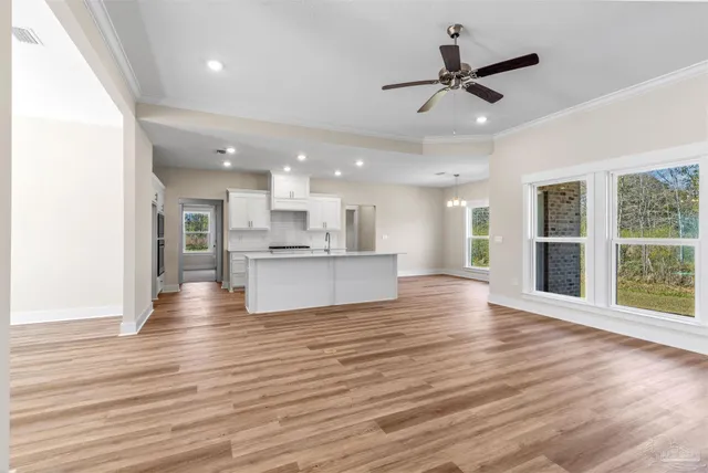 a view of an empty room with wooden floor and a kitchen