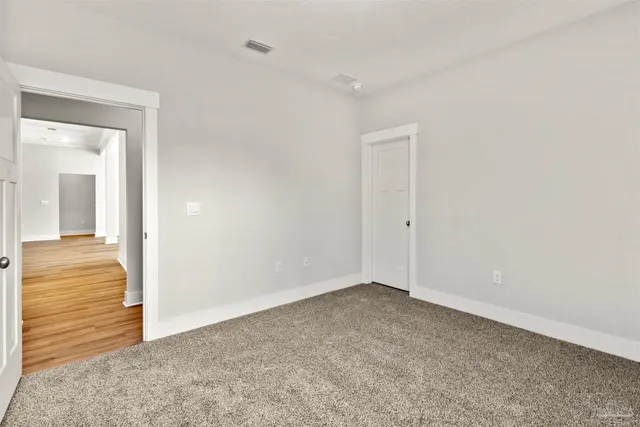 a view of an empty room with wooden floor fridge and a window