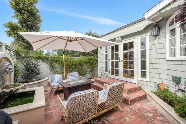 a view of a patio with couches chairs under an umbrella with a fire pit