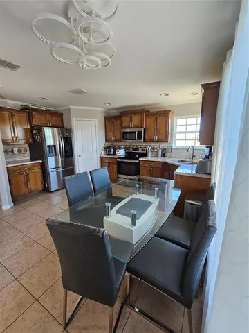 a view of a dining room with furniture a kitchen and chandelier