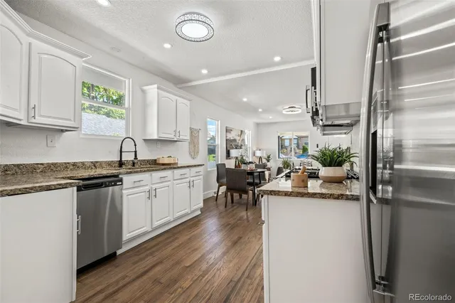 a kitchen with a sink dishwasher a refrigerator and cabinets with wooden floor