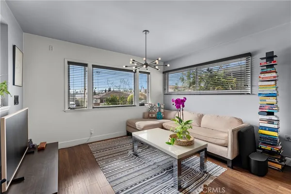 a living room with furniture a chandelier and a wooden floor
