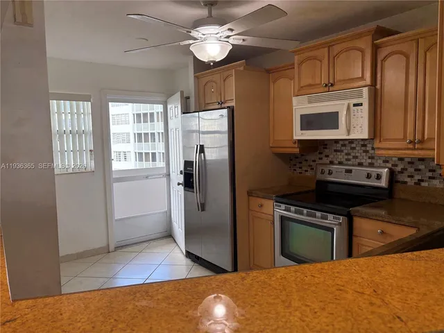 a kitchen with stainless steel appliances granite countertop a stove top oven a refrigerator a sink and dishwasher with wooden floor