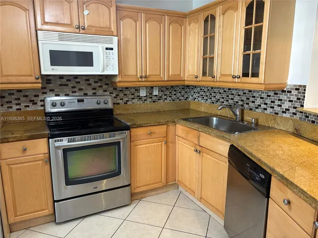 a kitchen with granite countertop a stove sink and cabinets