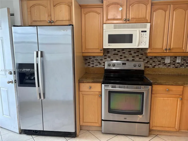 a kitchen with granite countertop white cabinets and stainless steel appliances