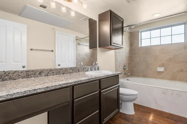 a bathroom with a granite countertop sink a toilet and bathtub