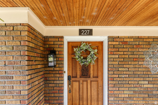227 West 200 North Logan, UT 84321 - Photo 9 of 44 Brick exterior featuring a wood-paneled ceiling, a wood entry door, and an exterior wall lantern
