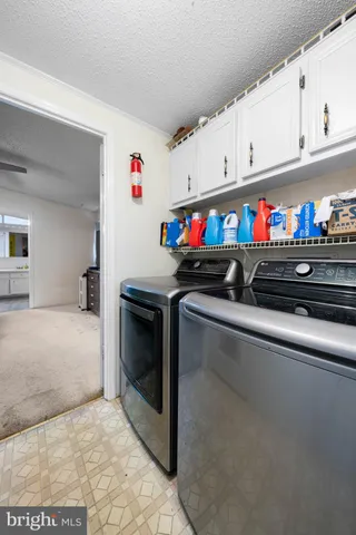 a utility room with stainless steel appliances granite countertop a sink dishwasher and white cabinets