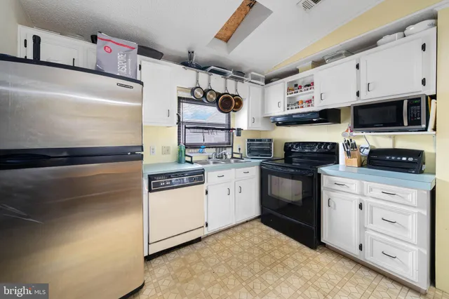 a kitchen with granite countertop a refrigerator stove and sink