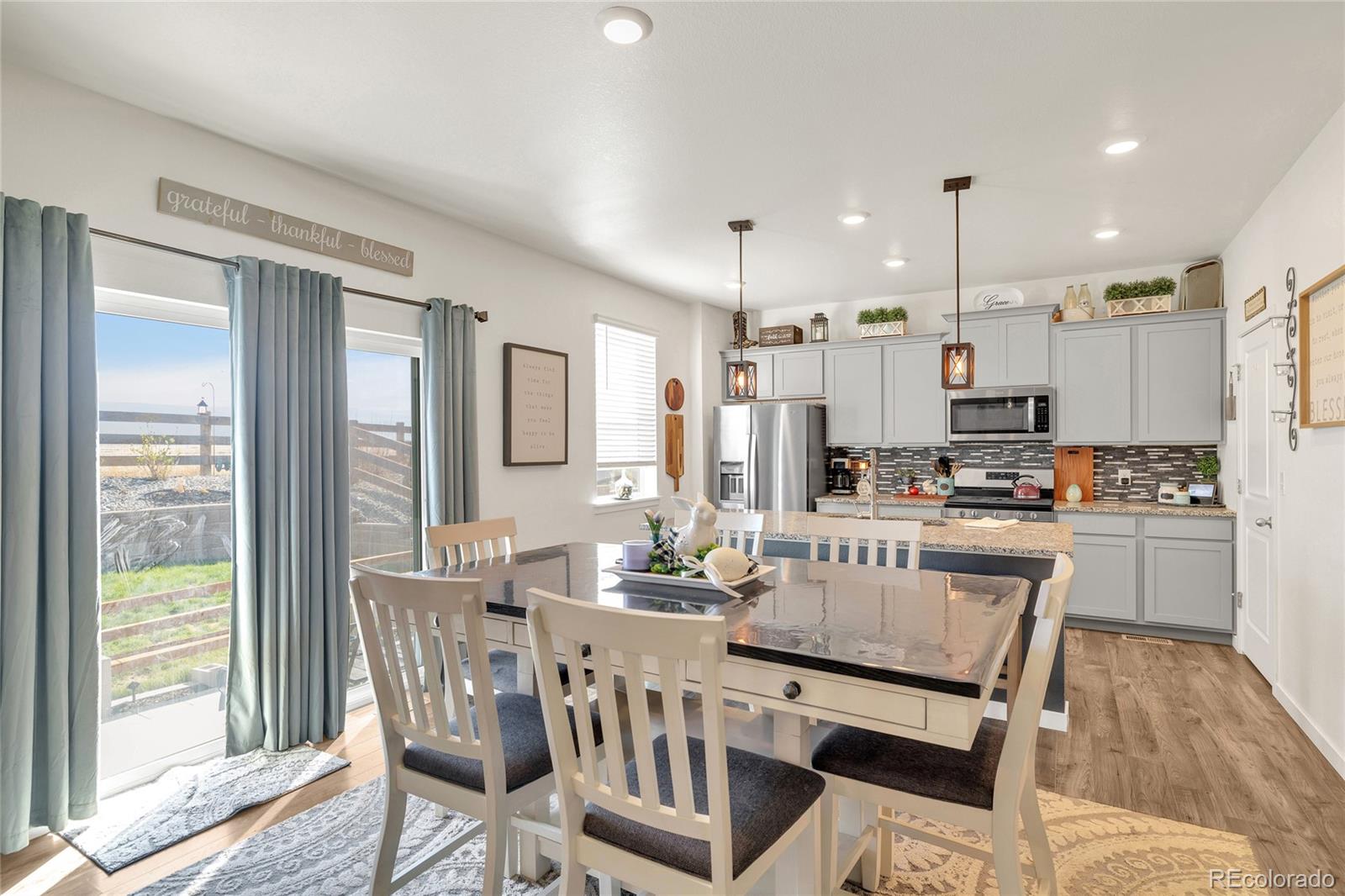 45824 Silverdrop Avenue Bennett, CO 80102 - Photo 15 of 49 a kitchen with kitchen island granite countertop a dining table chairs refrigerator and cabinets