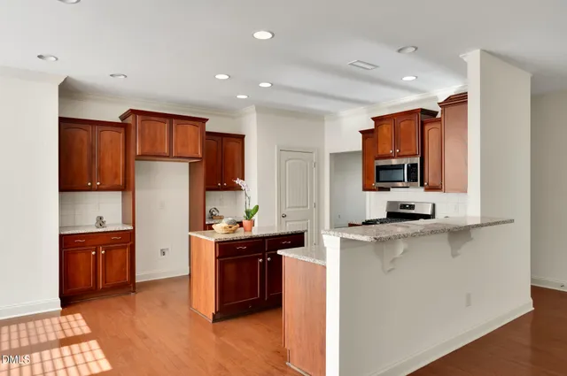 a kitchen with stainless steel appliances a sink a stove a refrigerator cabinets and a dining room