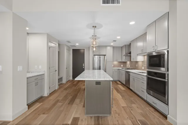 a large kitchen with kitchen island a sink stainless steel appliances and cabinets