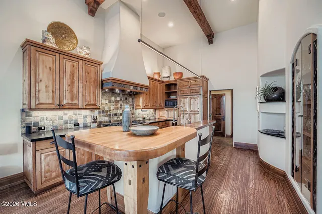 a kitchen with stainless steel appliances kitchen island granite countertop a table chairs in it and wooden floors