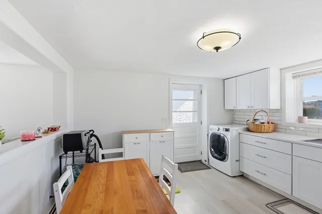 a kitchen with white cabinets and window