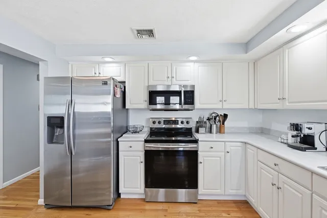 a kitchen with white cabinets and stainless steel appliances