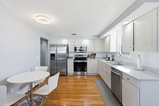 a large kitchen with cabinets wooden floor and stainless steel appliances