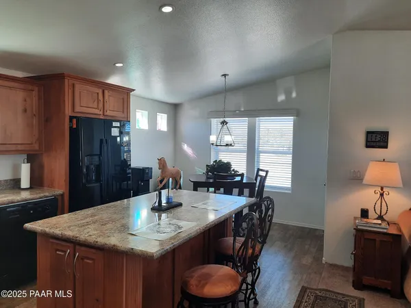 a kitchen with stainless steel appliances granite countertop a stove a sink a microwave a refrigerator and chairs