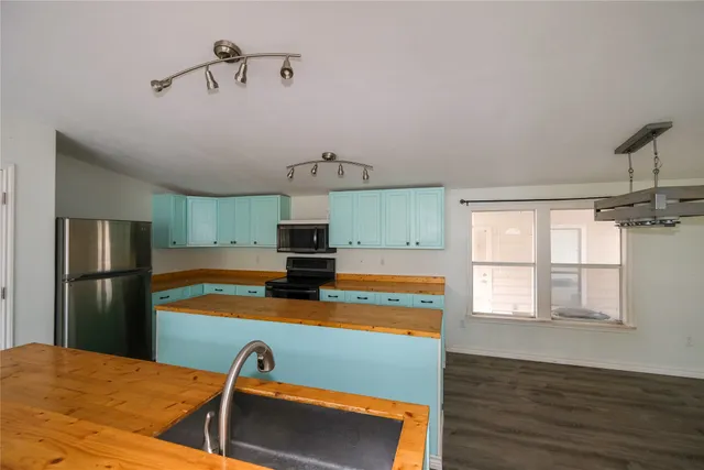 a kitchen with stainless steel appliances a stove top oven a sink with wooden floor and cabinets