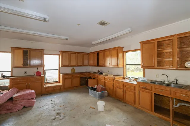 a large kitchen with kitchen island granite countertop a large window and white cabinets