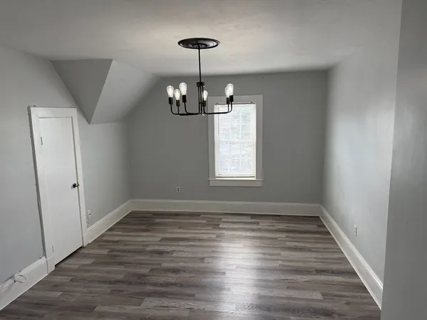 a view of empty room with wooden floor and window