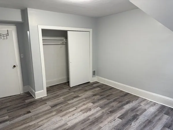 a view of an empty room with wooden floor and closet