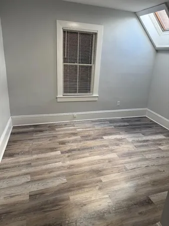 a view of empty room with window and wooden floor