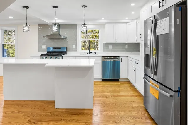 a large kitchen with stainless steel appliances a large counter top a stove a refrigerator and a sink