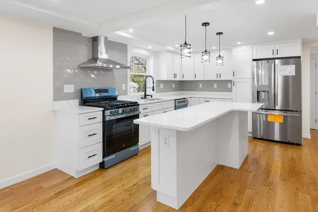 a kitchen with stainless steel appliances white cabinets and wooden floors