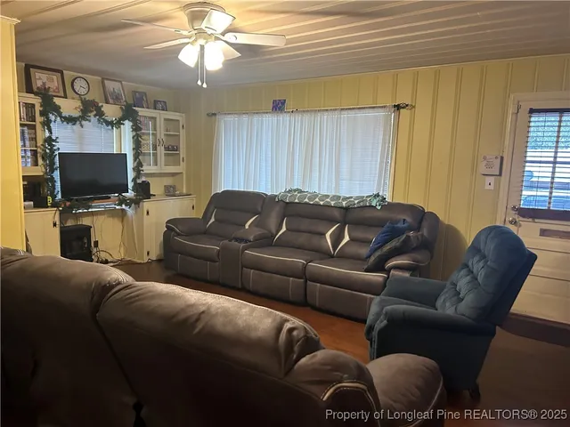 a living room with furniture a flat screen tv and a window