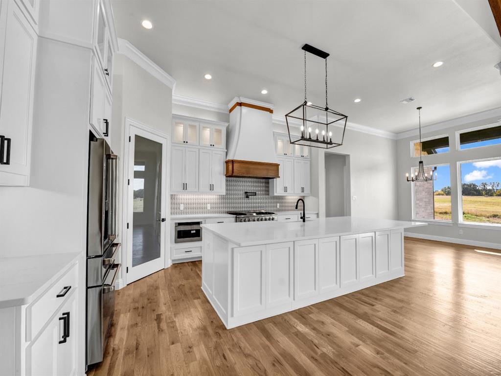 3009 Codigo Drive Weatherford, TX 76088 - Photo 15 of 40 a kitchen with stainless steel appliances a stove top oven a refrigerator a center island and a wooden floor
