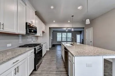 a kitchen with kitchen island granite countertop a stove and a sink