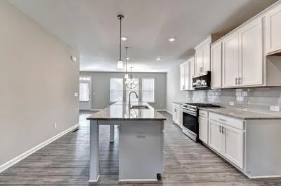 a kitchen with stainless steel appliances granite countertop a sink a stove and a wooden floors