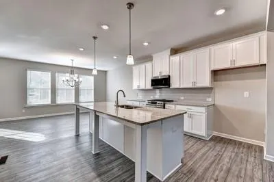 a kitchen with stainless steel appliances granite countertop a sink a stove a refrigerator and white cabinets with wooden floor