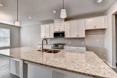 a kitchen with granite countertop a sink a counter top space appliances and cabinets