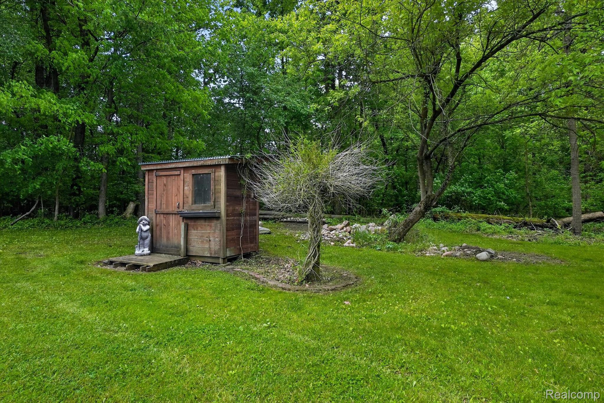 9565 Crofoot Road Fowlerville, MI 48836 - Photo 42 of 63 Wood-sided shed with a single window and corrugated metal roof, set on a raised platform