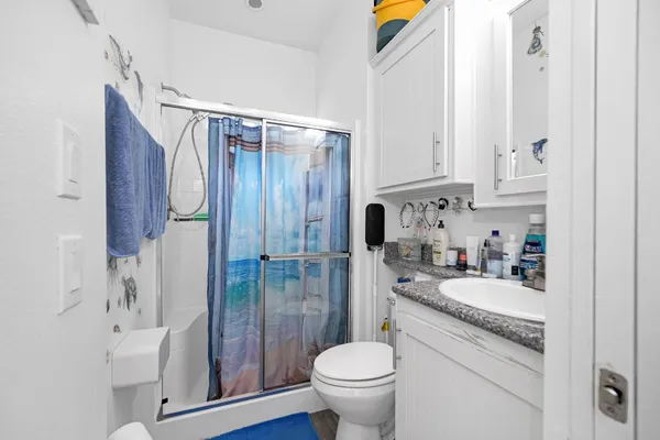 a bathroom with a granite countertop sink toilet and shower