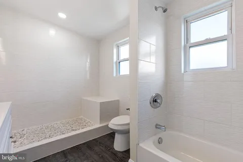 a bath room with a toilet a bath tub and a window