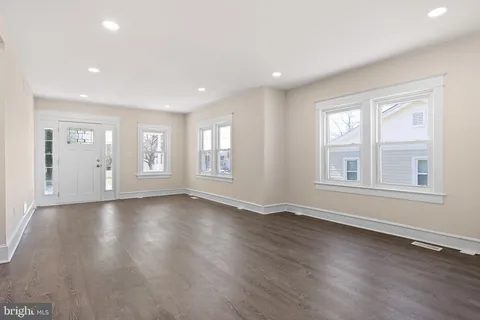 a view of an empty room with wooden floor and window