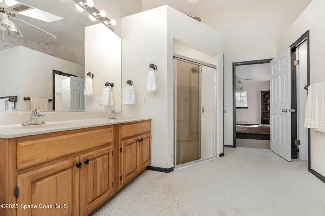a spacious bathroom with a double vanity sink a mirror and a shower