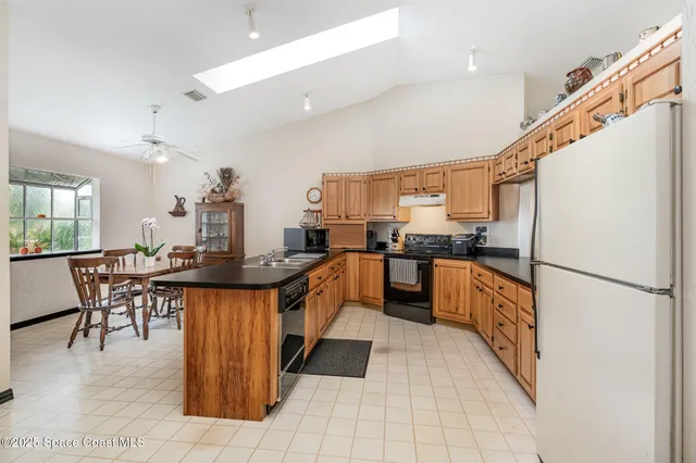 a kitchen with stainless steel appliances a stove a sink a refrigerator and chairs