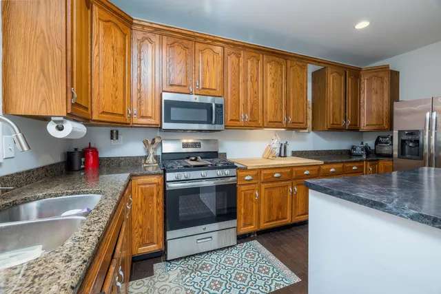 a kitchen with granite countertop wooden cabinets a stove top oven a granite counter top and stainless steel appliances