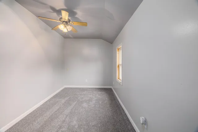 an empty room with a chandelier fan and windows