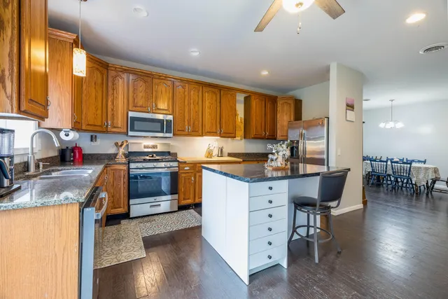 a kitchen with granite countertop a stove top oven a sink a dining table and chairs