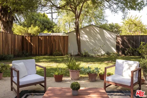 a view of backyard with table and chairs and wooden fence