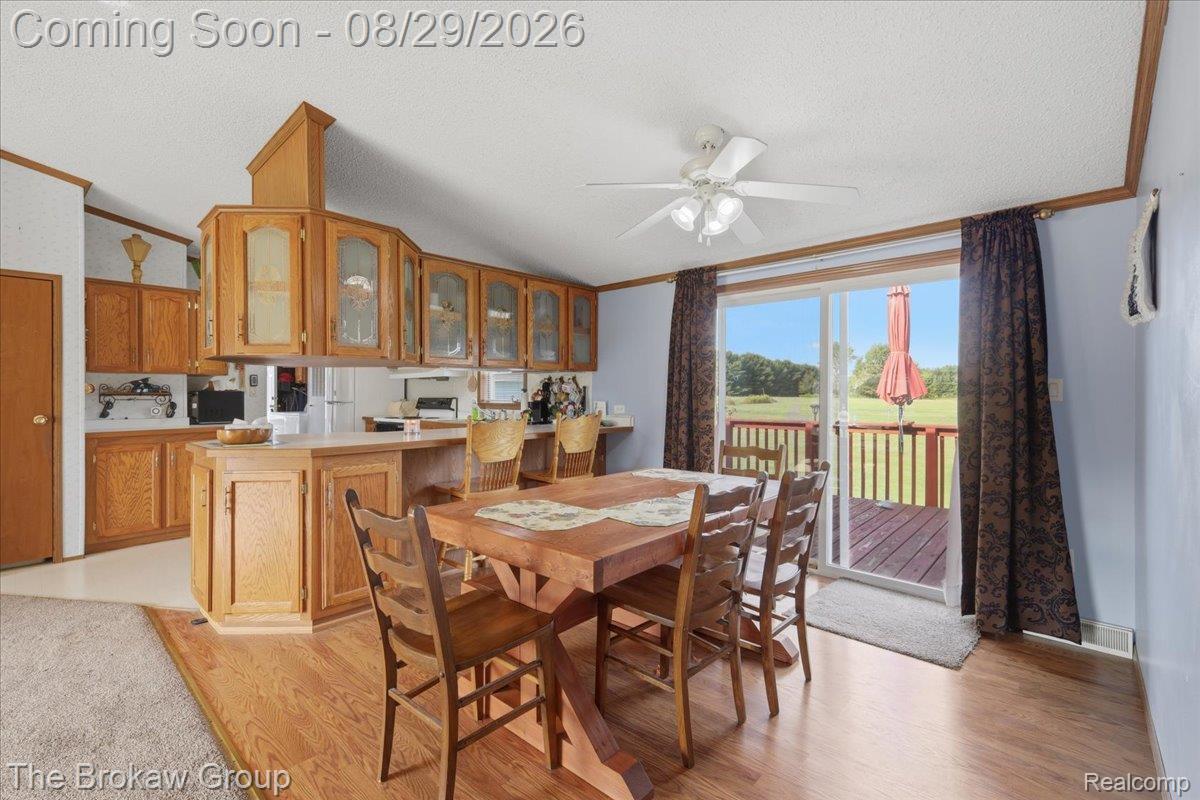 5189 North Webster Road Flushing, MI 48433 - Photo 15 of 46 Kitchen and dining area featuring wood-finish flooring, wood cabinetry with glass-front accents, a ceiling fan, and sliding glass doors to an outdoor deck