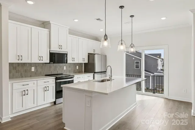 a large kitchen with stainless steel appliances kitchen island granite countertop a sink a stove and a wooden floors