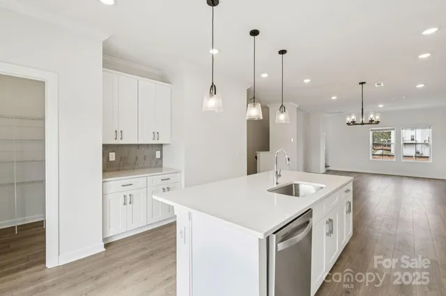 a large white kitchen with a stove a sink a center island and wooden floor