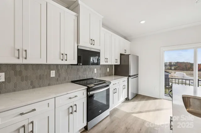 a kitchen with stainless steel appliances granite countertop white cabinets and window
