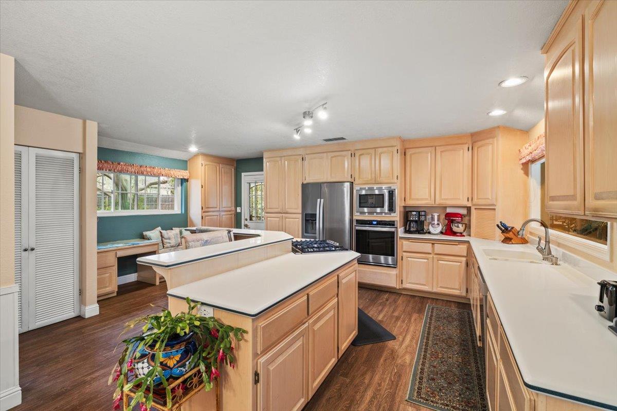 Spacious kitchen features hardwood maple cabinetry w/pullouts, Corian counter-tops, separate electric oven, gas 5 burner cooktop, large pantry cabinet w pull-outs and separate pantry closet.